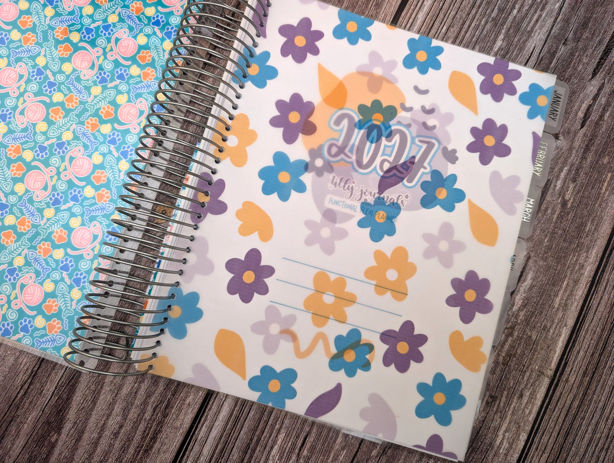 A colorful 2016-themed spiral-bound notebook with a floral pattern is placed on a wooden surface.