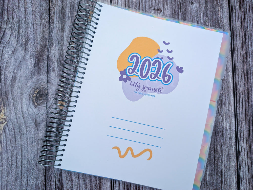 a spiral-bound notebook with a colorful cover, resting on a wooden surface.