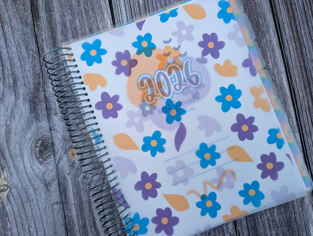 A colorful 2016-themed spiral-bound notebook with a floral pattern is placed on a wooden surface.
